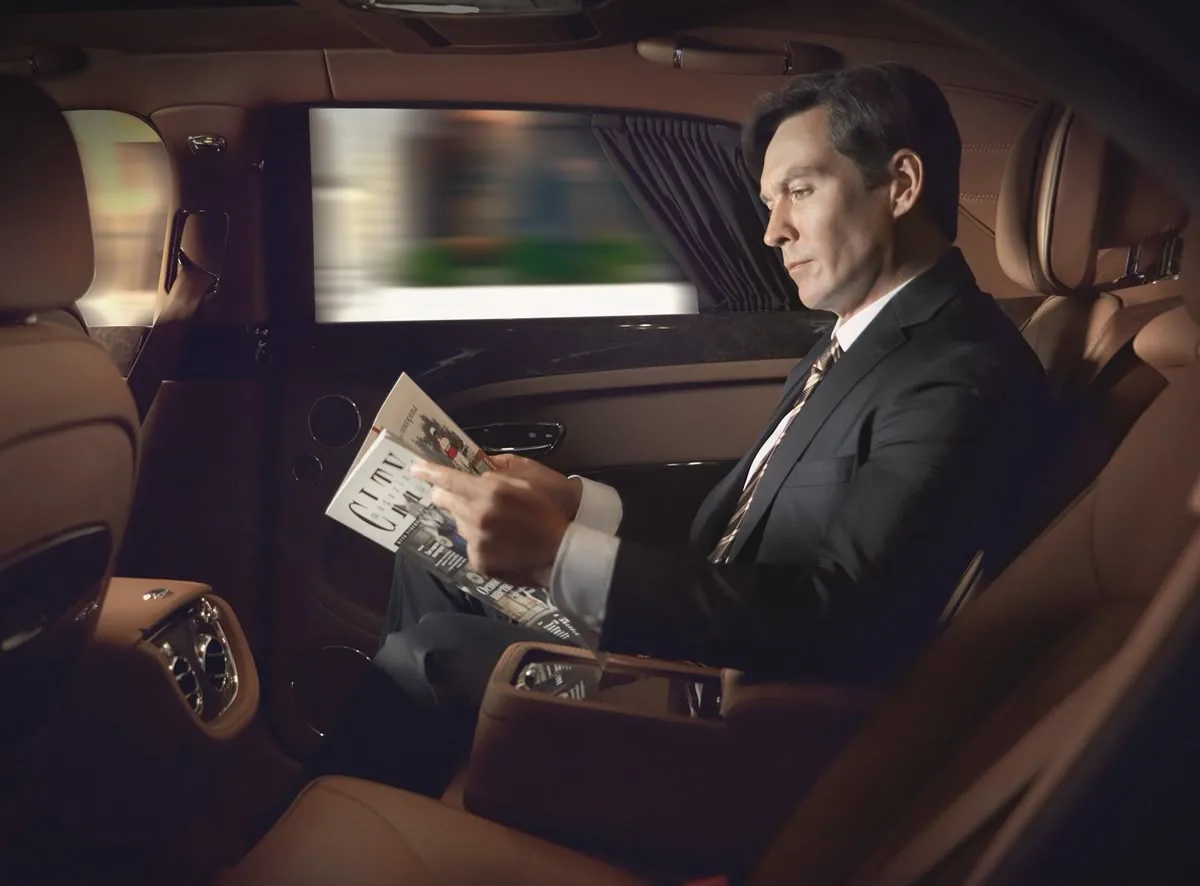 Passenger reading in the rear cabin of a chauffeured car