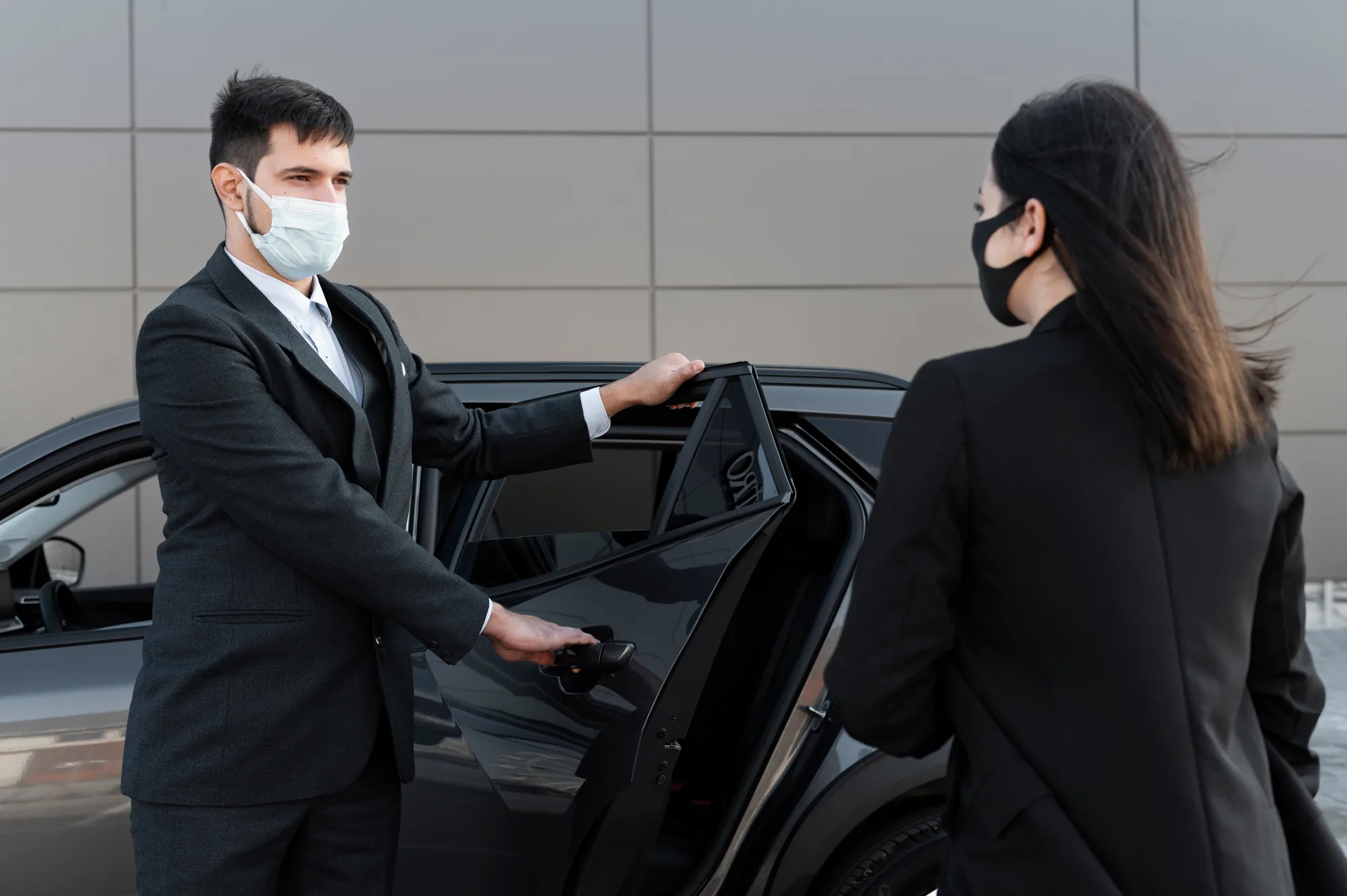 Chauffeur opening a car door for a client at the kerbside