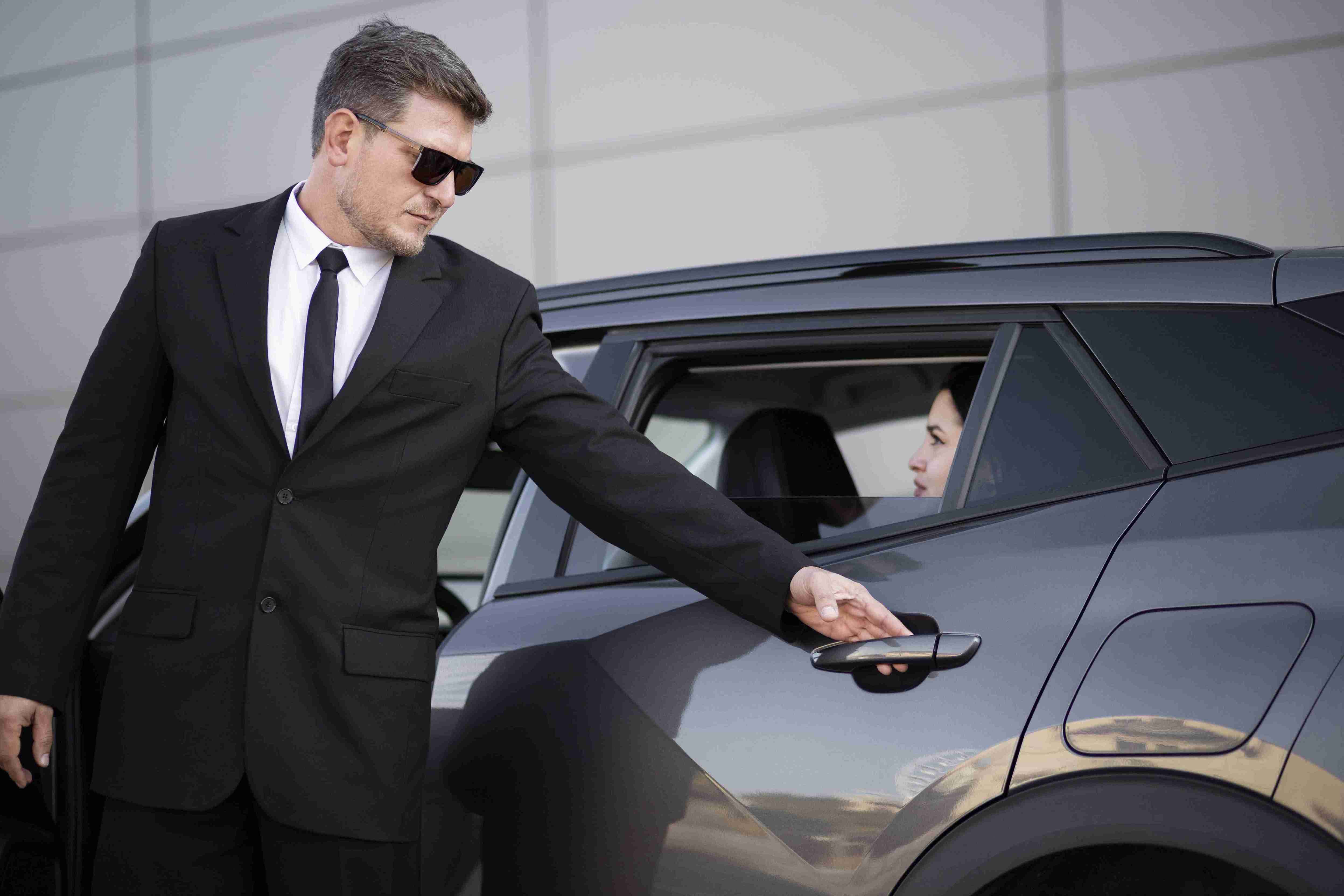 Professional chauffeur opening the door of a luxury vehicle